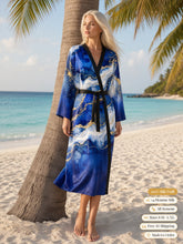 Load image into Gallery viewer, Woman standing beside a palm tree on a white-sand beach in the Royal Lapis silk peignoir, ombré cuff and hem style with black trim and tie