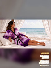 Load image into Gallery viewer, Woman reclining on a beachside daybed in the Purple Heartstone silk peignoir, ombré cuff and hem style with black trim and tie