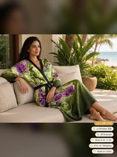 Load image into Gallery viewer, Woman lounging on a veranda sofa in the Sunken Atlantis silk peignoir, ombré cuff and hem style with black trim and tie