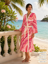 Load image into Gallery viewer, Woman standing at a stone balustrade above the beach in the Blush Hollow silk peignoir, classic style with ivory trim and tie