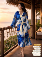 Load image into Gallery viewer, Woman on a thatched beach pavilion deck at sunset in the Royal Lapis silk peignoir, classic style with ivory trim and tie
